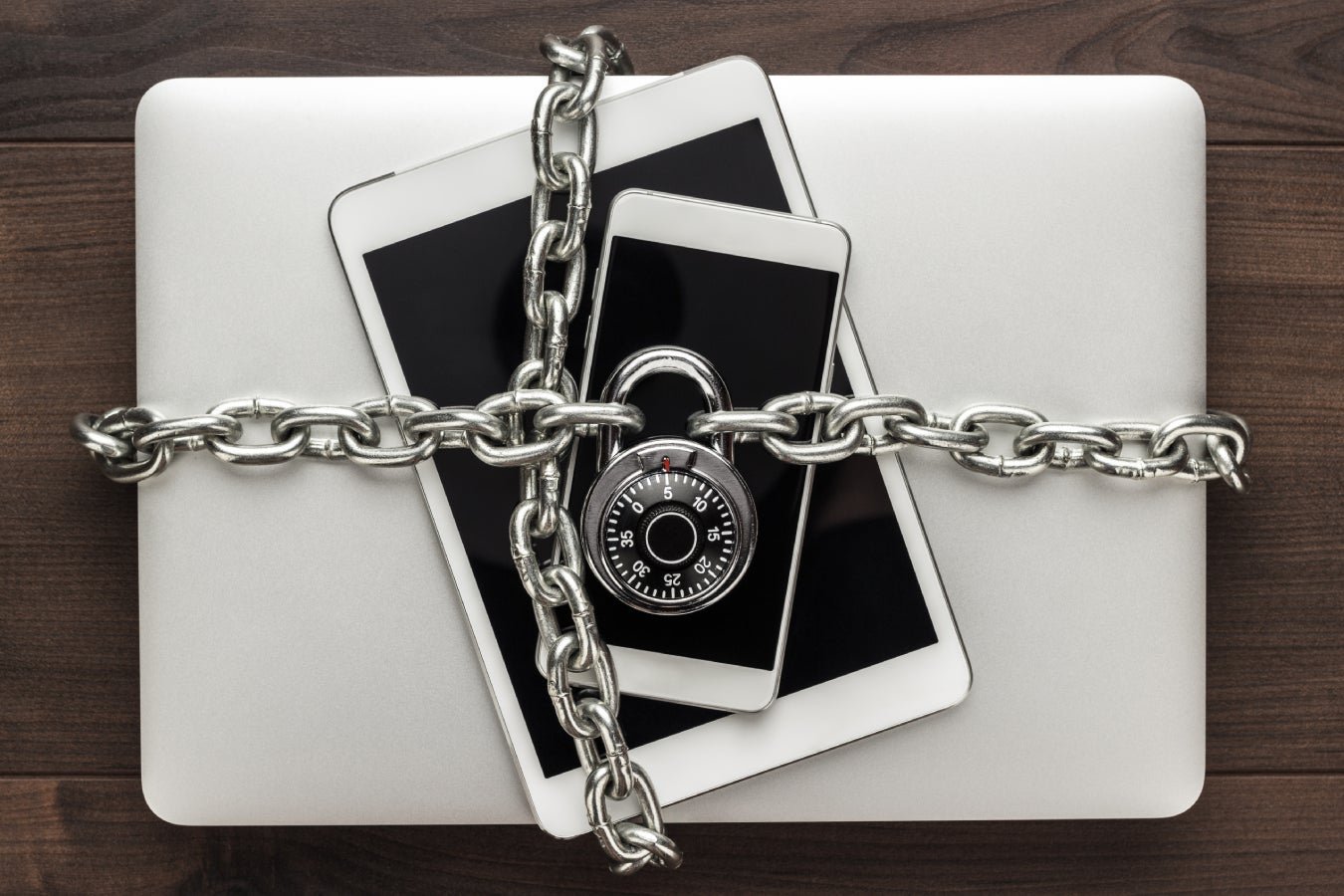 Um telefone, tablet e laptop acorrentado e trancados.
